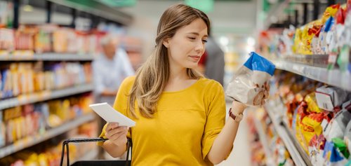 Frau in gelbem Pullover wählt Produkt im Supermarkt aus. Die Verbraucher-Plattform des Markenverbandes